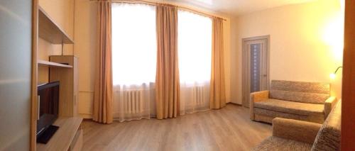 a living room with a chair and a large window at Apartament na Vielikoy in Velikiy Novgorod