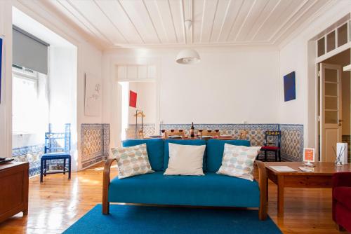 uma sala de estar com um sofá azul e uma mesa em ALTIDO Classic 3BR home with workspace in Chiado, 2mins from Baixa-Chiado subway em Lisboa