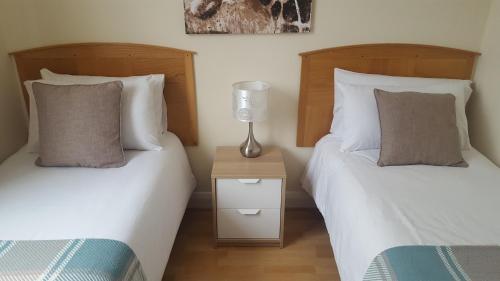 a bedroom with two beds and a lamp on a night stand at Kathleen House in Enfield