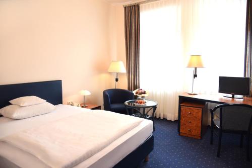 a hotel room with a bed and a desk at Hotel Arkadia in Friedrichsdorf