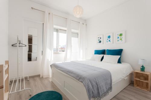 リスボンにあるFLH Marques Modern Flatの白いベッドルーム(青色をアクセントにした大型ベッド1台付)