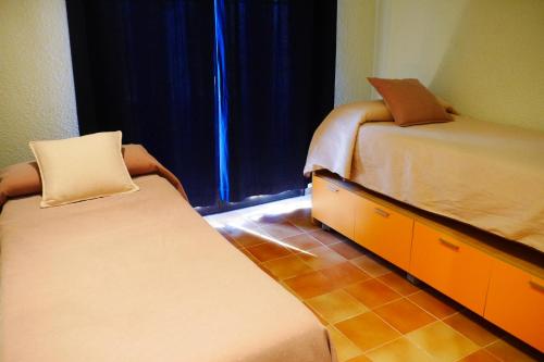 a bedroom with two beds and a dresser and a window at Hotel Restaurant El Bosc in Banyeres del Penedes