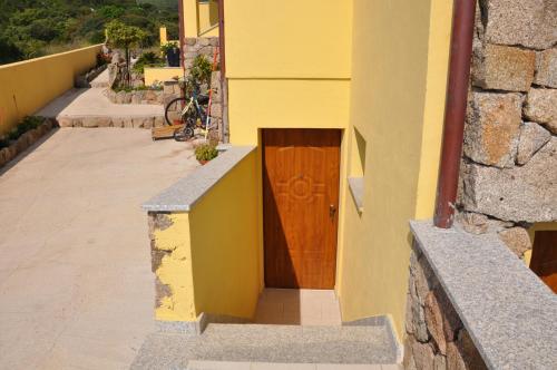 un edificio amarillo con una puerta de madera. en Sa Mamma e Sole B&B, en Cala Gonone