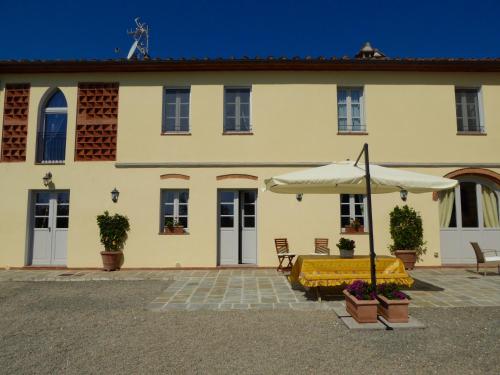 a large building with a table and an umbrella at Casa Vacanze Villa Cerine in Altopascio