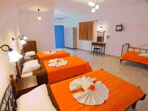 two beds in a room with orange sheets at Ios Memories in Mylopotas