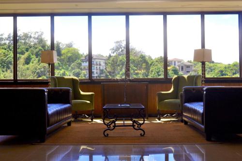 a waiting room with chairs and a table and windows at Crosswinds Nature View Suite in Tagaytay