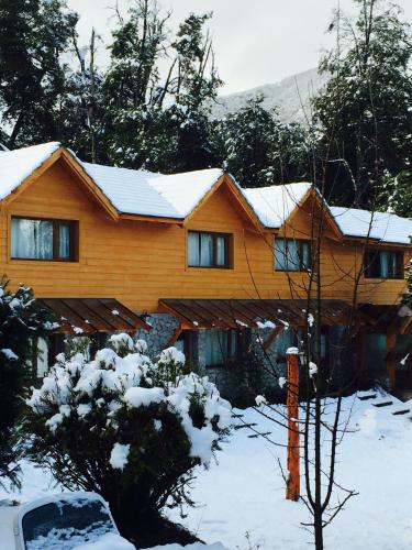 a house with snow on the roof of it at Encanto del Rio in Villa La Angostura