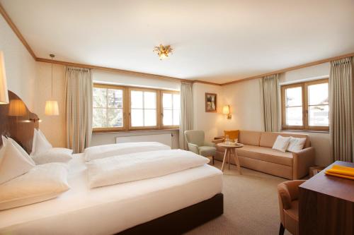 a hotel room with two beds and a couch at Hotel Sonnenburg in Lech am Arlberg