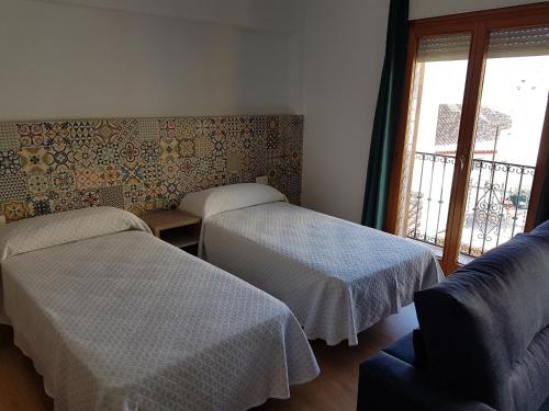 ベニドルムにあるApartamentos El Castellのベッド2台、ソファ、窓が備わる客室です。
