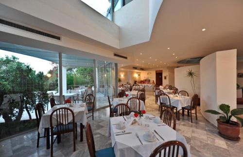 a restaurant with white tables and chairs and glass walls at Rodon Hotel in Chania Town