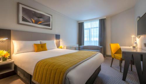a hotel room with a bed and a desk at Maldron Hotel Dublin Airport in Cloghran