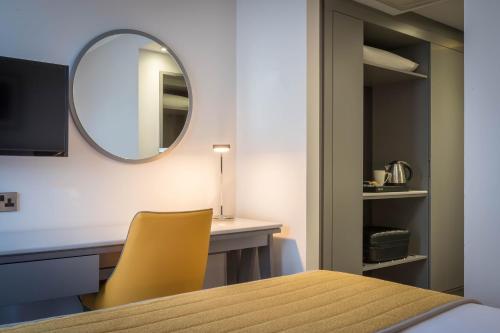 a dining room with a table and a mirror at Maldron Hotel Dublin Airport in Cloghran