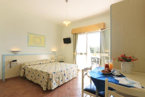 リド・マリーニにあるVillaggio Resort Arco Del Saracinoのベッドルーム1室(ベッド1台、テーブル、青いテーブルクロス付)