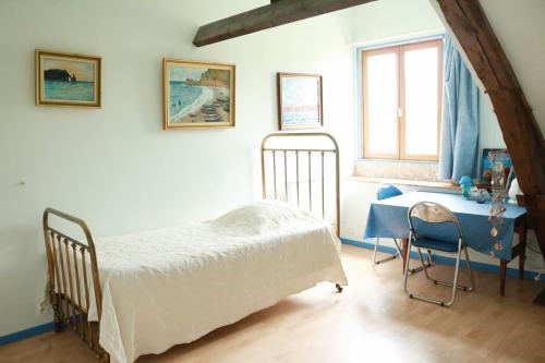 a bedroom with a bed and a desk and a window at Chambres d'Hôtes " Le Clos des Colimaçons " in Maniquerville