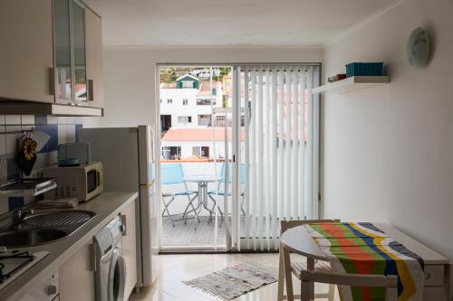 uma pequena cozinha com uma mesa e uma varanda com vista em Casa de Hóspedes Porto Pim em Horta