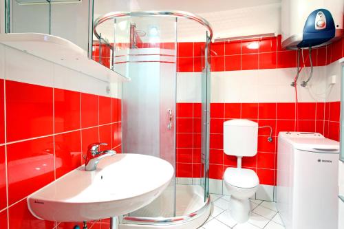 uma casa de banho vermelha e branca com um lavatório e um WC em Penthouse Alma Vivoda em Piran