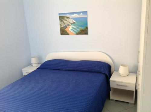 ein Schlafzimmer mit einem blauen Bett und zwei Nachttischen in der Unterkunft Appartamenti Scala Dei Turchi Villa Saporito in Realmonte