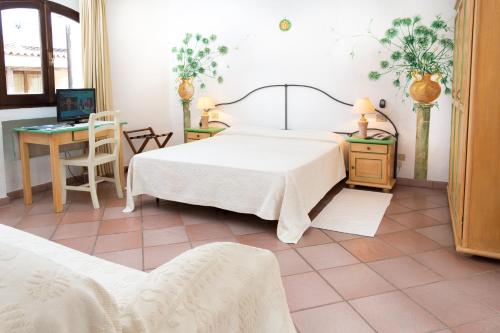 1 dormitorio con cama, mesa y escritorio en La Jacia Hotel & Resort, en Baja Sardinia
