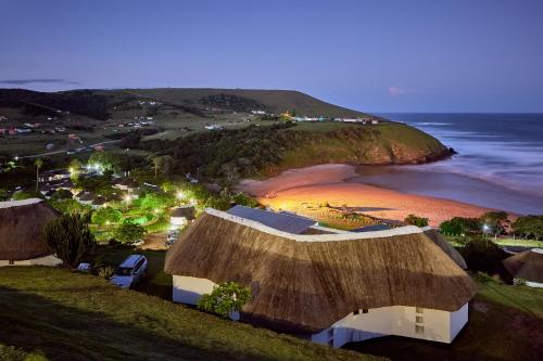 an overhead view of a beach with a grass roof at First Group Hole in the Wall in KuGqangushe