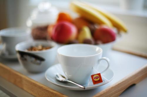 a cup of coffee sitting on a counter with fruit at The Green Apartments in Magarevo