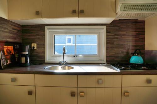 a kitchen with a sink and a window at Camping Bissen in Esch-sur-Sûre