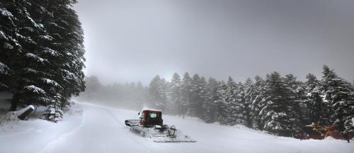 a snow truck driving down a snow covered road at The Green Apartments in Magarevo