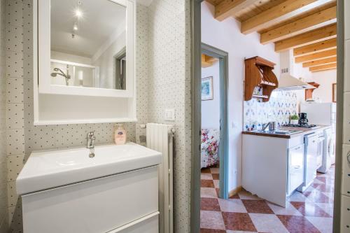a bathroom with a white sink and a kitchen at Le Camerine Apartment Water Front in Toscolano Maderno