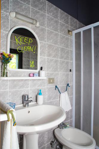 ein Badezimmer mit einem weißen Waschbecken und einem Spiegel in der Unterkunft Lako Hostel in Capodimonte