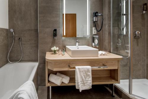 y baño con lavabo, ducha, bañera y lavamanos. en Hotel-Restaurant Distlerhof, en Leinburg