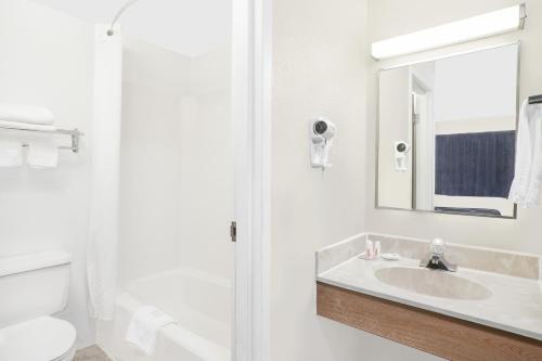 Baño blanco con lavabo y espejo en Super 8 by Wyndham Middletown en Middletown