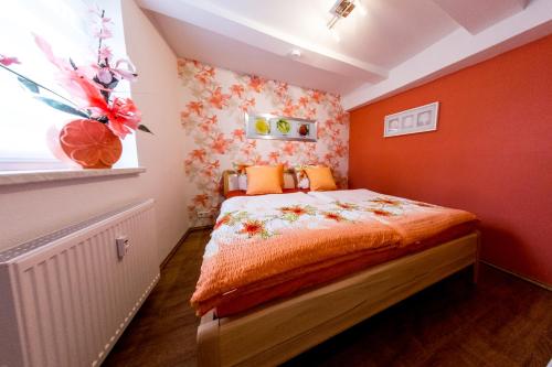 a bedroom with a bed with orange walls and a window at harz-traum in Gernrode - Harz