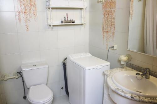 een witte badkamer met een toilet en een wastafel bij La Marina Suite in Acantilado de los Gigantes