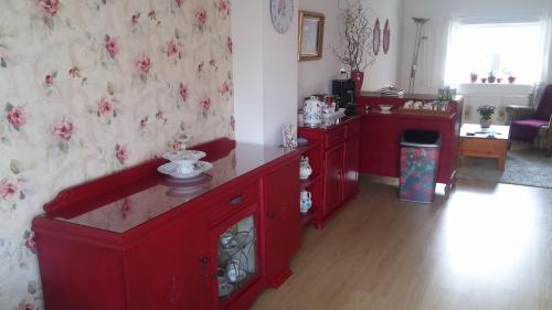 a kitchen with red cabinets and a living room at Bed en Broodje Bloem in Delft