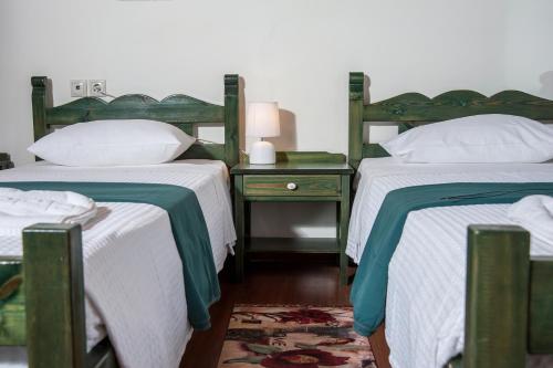 two beds with green and white sheets in a room at Kyriaki's Cozy Apartments in Agia Marina Nea Kydonias