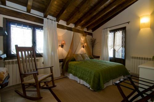 een slaapkamer met een bed, een stoel en ramen bij Casa Tio Conejo in San Román de Cameros