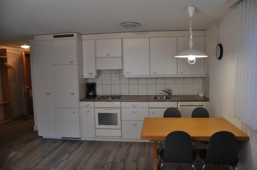 ツェルマットにあるAlcamarの白いキャビネット、テーブルと椅子付きのキッチンが備わります。