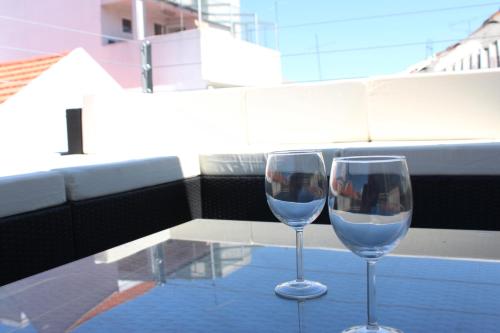 two wine glasses sitting on a table on a balcony at Penthouse Oasis in Setúbal