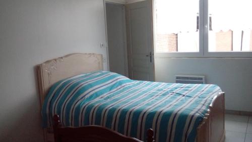 a bedroom with a bed with a striped blanket on it at Gîte de Blessy in Blessy