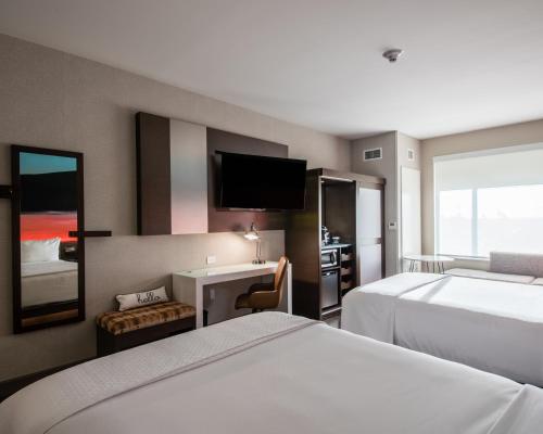 a hotel room with two beds and a desk and a tv at Cambria Hotel McAllen Convention Center in McAllen