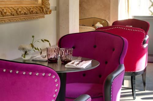 a table with pink chairs and a table with glasses on it at La Villa Haussmann in Paris