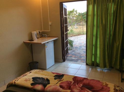 1 dormitorio con 1 cama, lavamanos y puerta en Klein Paradys Lodge - Polokwane, en Polokwane