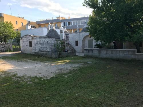 an old stone building with a yard and a tree at Il Trullo Di Santanna in Locorotondo