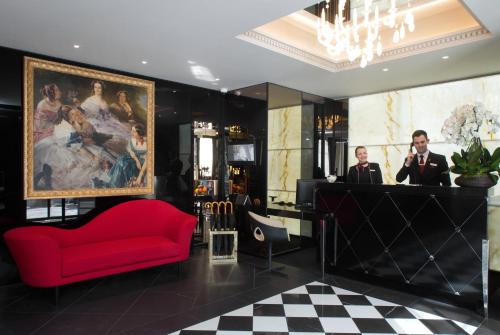 a lobby with a red couch and a man standing at a bar at La Villa Haussmann in Paris