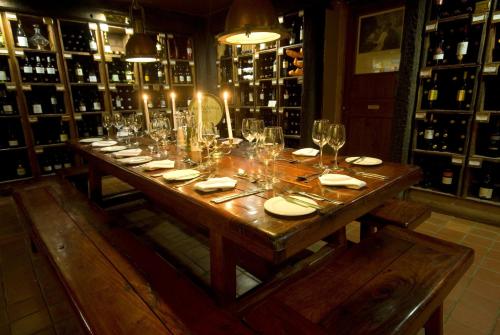 a long wooden table in a wine cellar with glasses at Granny Mouse Country House & Spa in Balgowan