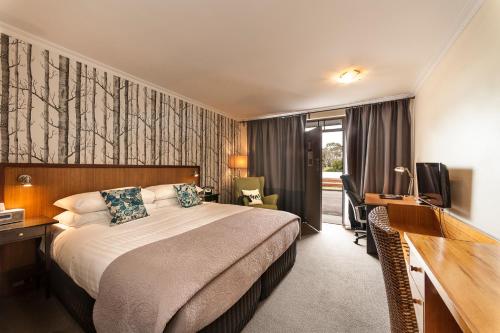 um quarto de hotel com uma cama, uma secretária e uma televisão em The Waterfront Wynyard em Wynyard