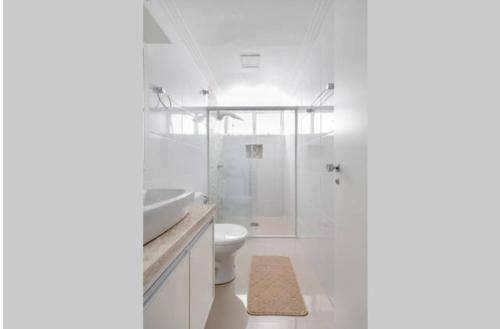 a white bathroom with a toilet and a sink at Top Floripa Apartment in Florianópolis