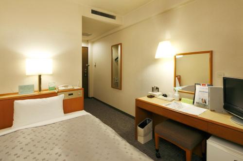 Habitación de hotel con cama y escritorio con ordenador en Hotel Lexton Kagoshima Annex, en Kagoshima