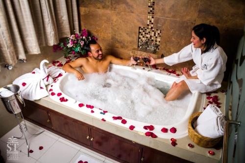 a man and a woman sitting in a bath tub with wine at Hotel Suites Teziutlan in Teziutlán