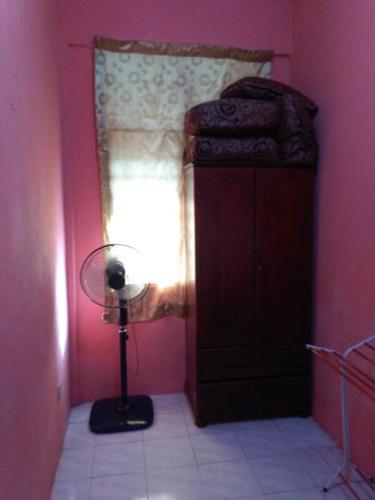 a room with a bedroom with a window and a fan at Deenaz Utara Homestay in Alor Setar