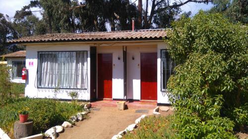 una pequeña casa con una puerta roja y blanca en American Hotel en Los Vilos